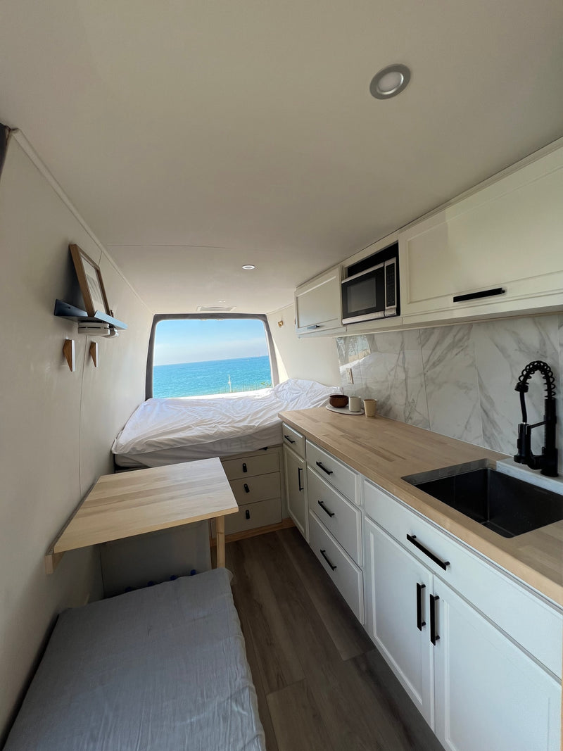 Spacious RV rental interior with bed offering ocean views, kitchenette, and dining area. — photo 1