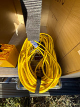 RV rental gear: Yellow extension cord & leveling blocks stored in a camper compartment.