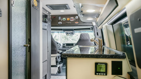Spacious yet compact RV rental interior: a modern kitchen with sink and controls, leading to the driver's cockpit.