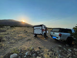 Experience the freedom of an RV rental: a travel trailer and pickup truck at sunset in a vast desert.