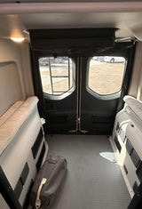 RV rental: Rear interior of a camper van, featuring side benches/beds, open floor space, and rear doors. Ready for adventure!