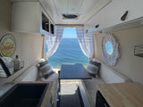 Inside an RV rental camper van: A cozy dining area, kitchen, and incredible ocean views out the back.