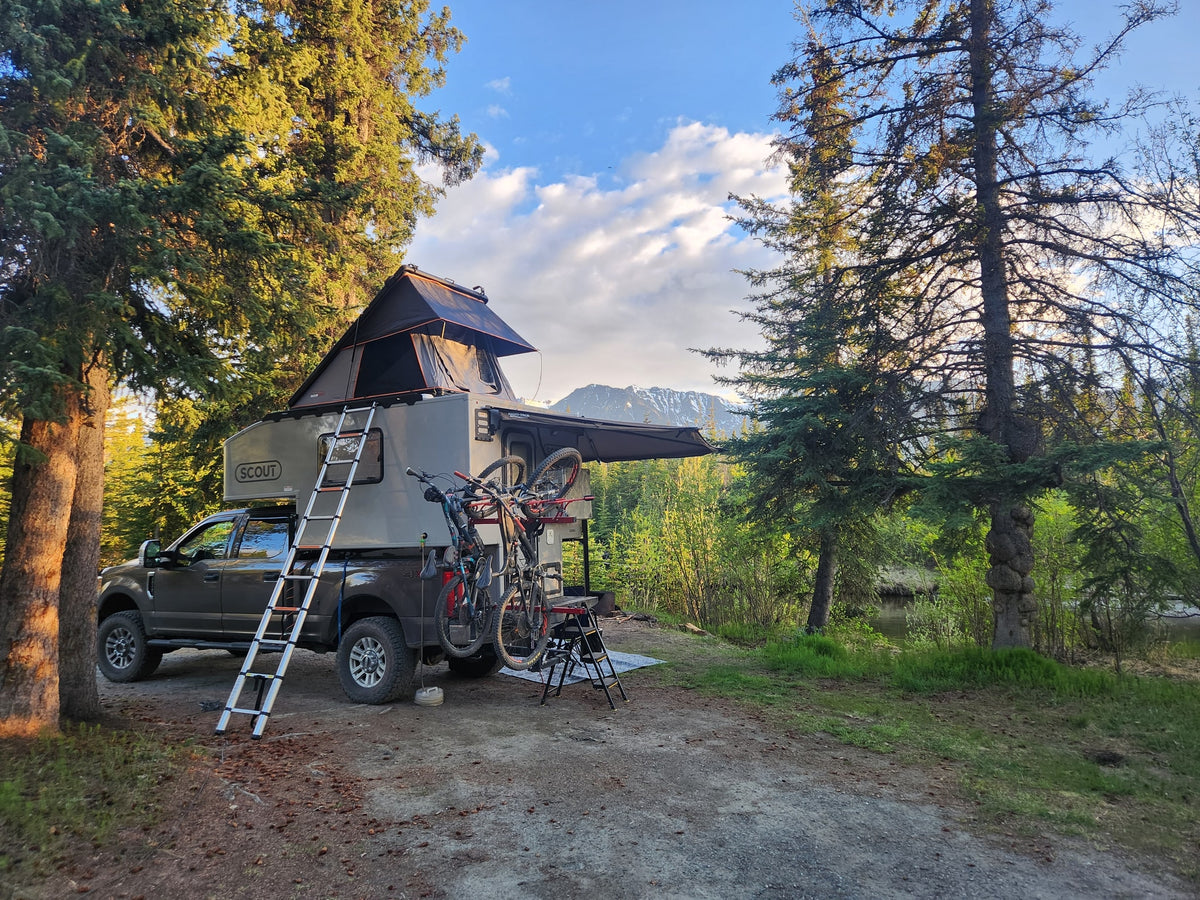An RV rental truck camper with rooftop tent and bikes