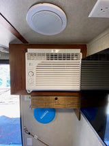 RV rental: custom-fitted window AC unit, ceiling speaker, and handy shelf. Comfort and convenience inside.