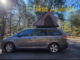 Minivan RV rental with a roof-top tent in a sunny forest setting. Great for camping! E-Bikes available.