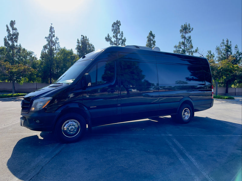 Black Mercedes Sprinter 3500 van for rv rental, parked in a sunny lot with trees in background. — photo 6