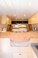 Spacious and cozy interior of an RV rental, featuring a comfortable bed, storage, and modern lighting.