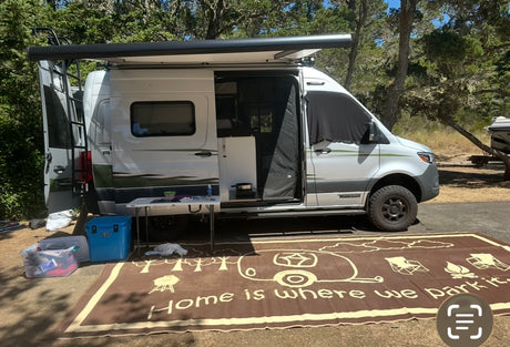 This Winnebago camper van RV rental is perfectly set up for camping. An awning shades the outdoor table, cooler, and camp mat.