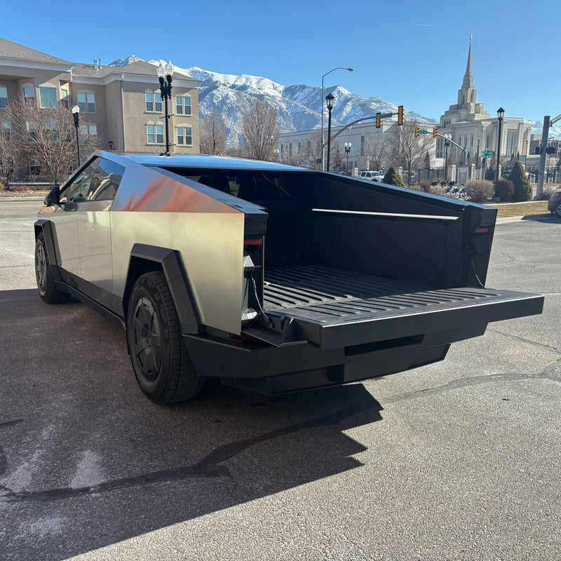 A unique Tesla Cybertruck with its tailgate open, hinting at versatile utility. Set against mountains & a temple, it challenges typical rv rental concepts. — photo 6