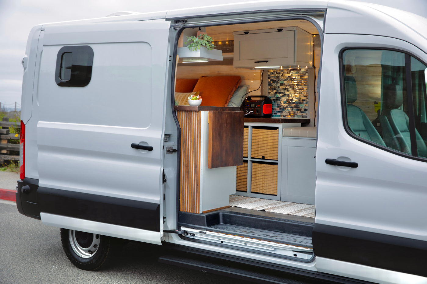 RV rental: A white converted camper van with its side door open, revealing a cozy interior with bed, storage, and lights. — photo 3