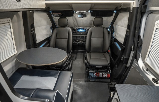 RV rental interior: front cabin with swiveling seats, a round dinette table, and cozy bench seating for comfortable travel.