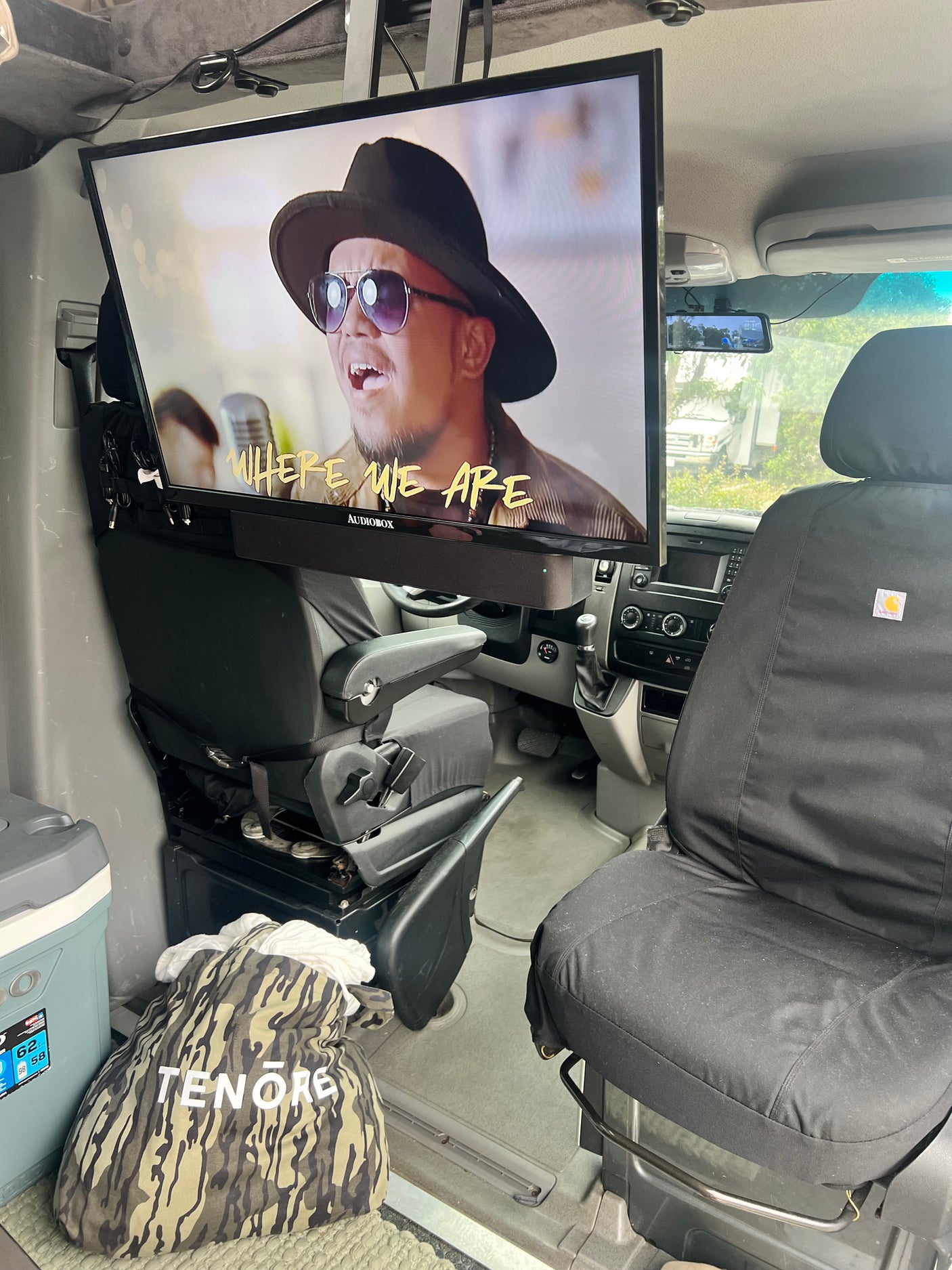 Inside an RV rental: Custom interior with a large TV featuring a music video, swivel seat, and cooler for on-the-road comfort.