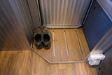RV rental interior: Shoes on a wooden entry floor with a built-in drying area and safety detector.
