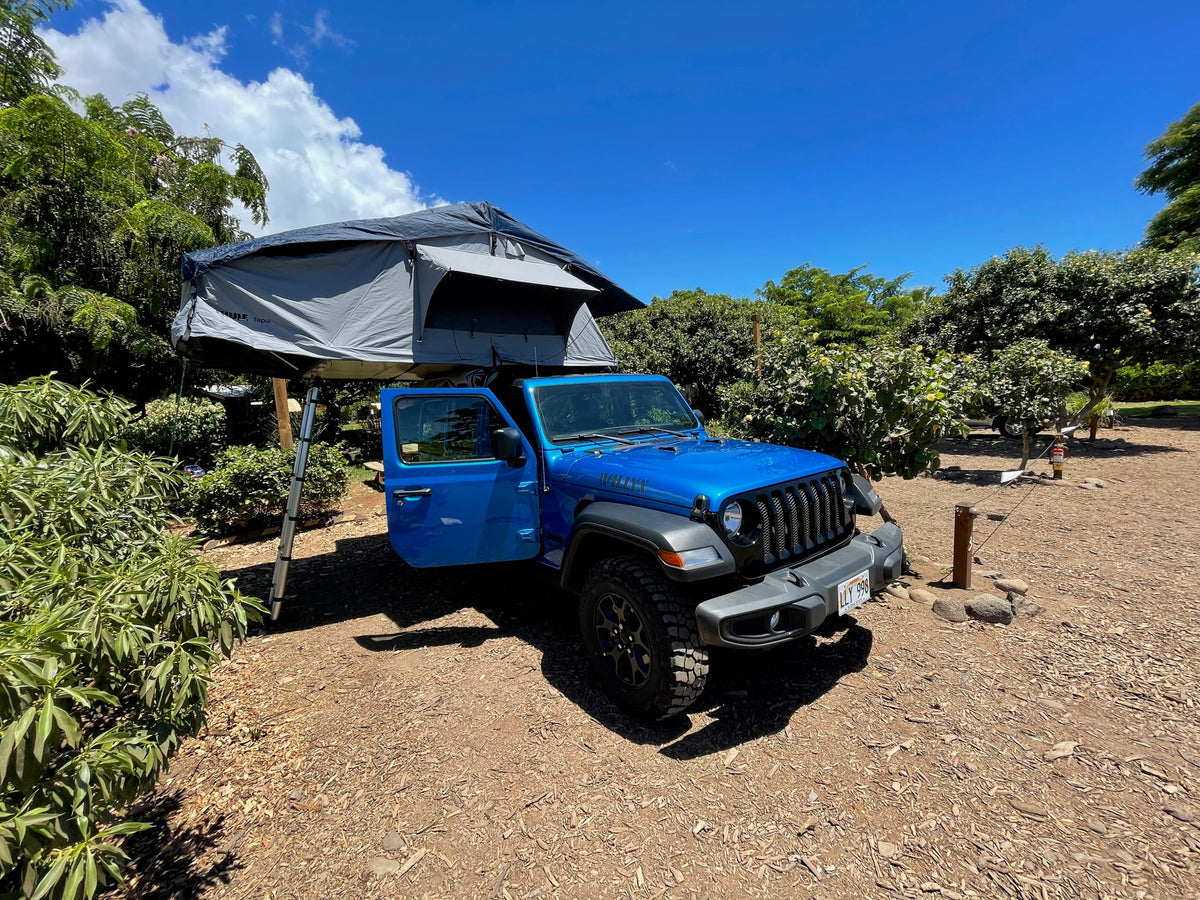 Blue Jeep with a rooftop tent deployed, like an RV rental for camping adventures under clear skies. — photo 18