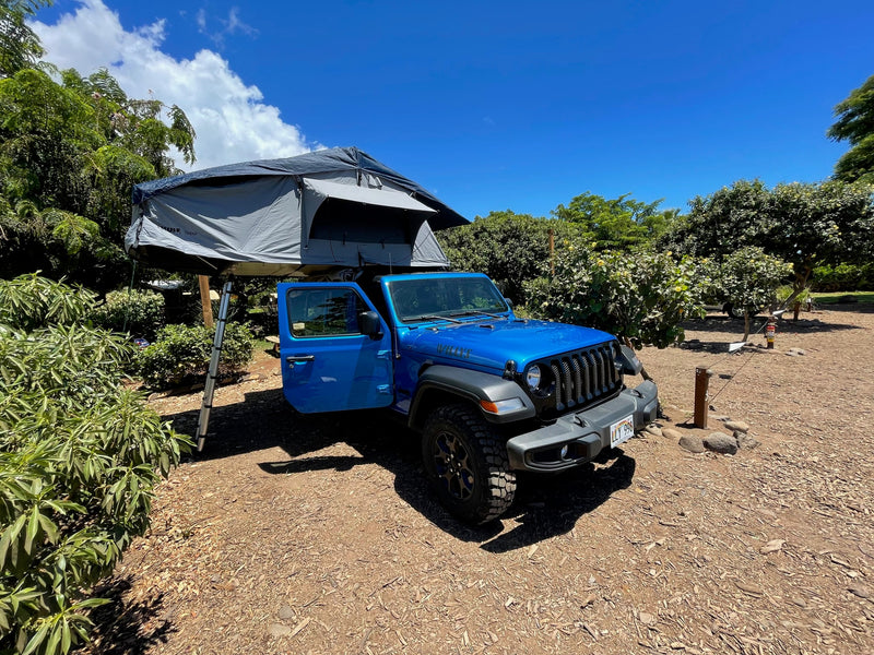 Blue Jeep with a rooftop tent deployed, like an RV rental for camping adventures under clear skies. — photo 18