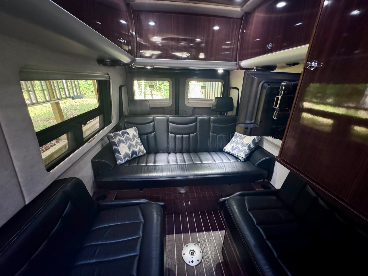 Experience comfort in this RV rental's interior, featuring plush leather seating, elegant wood cabinets, and ample natural light.