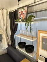 Cozy RV rental interior featuring decorative shelves with a cow picture, plants, glasses, and black bowls.