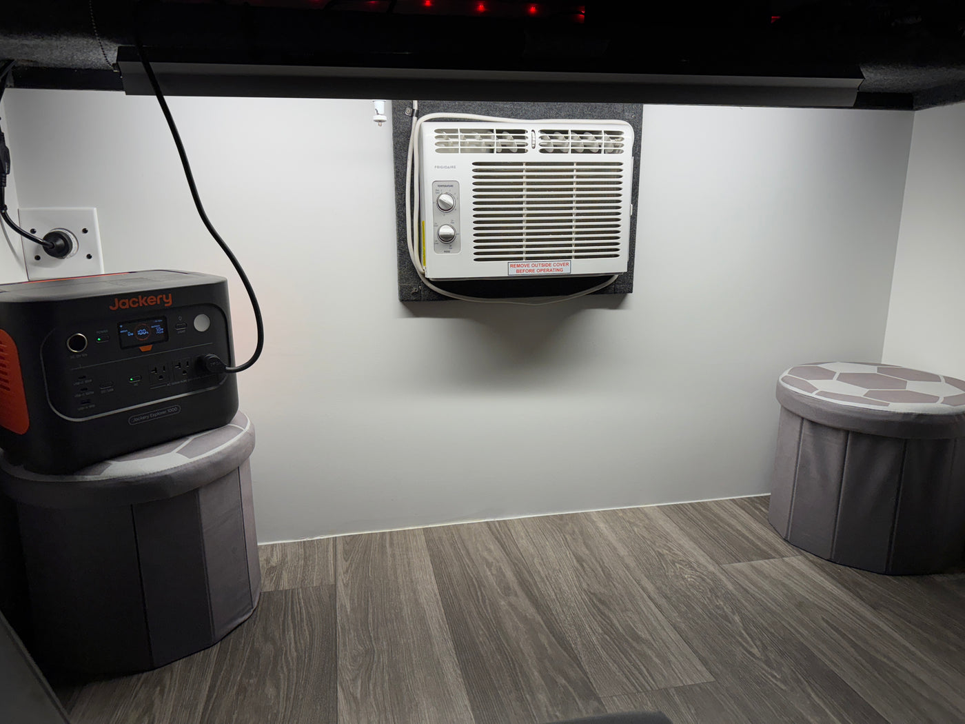 This RV rental interior features a Jackery portable power station, a Frigidaire AC unit, and storage stools, for compact living. — photo 9