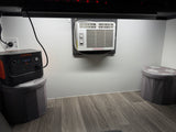 This RV rental interior features a Jackery portable power station, a Frigidaire AC unit, and storage stools, for compact living.