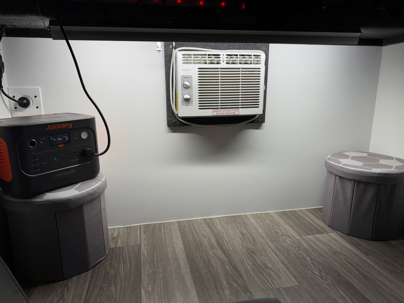 This RV rental interior features a Jackery portable power station, a Frigidaire AC unit, and storage stools, for compact living. — photo 9