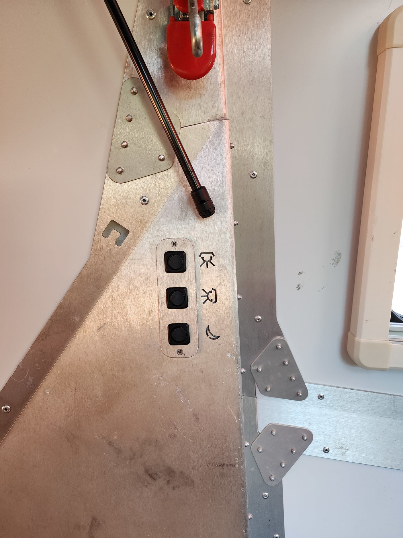 RV rental interior: A sturdy, riveted metal control panel with black buttons for light settings (sun, moon symbols) and a red handle.