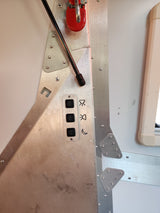 RV rental interior: A sturdy, riveted metal control panel with black buttons for light settings (sun, moon symbols) and a red handle.