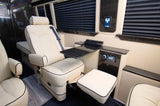 Luxury RV rental interior featuring a cream captain's chair with quilted upholstery, a footrest, and a built-in table.