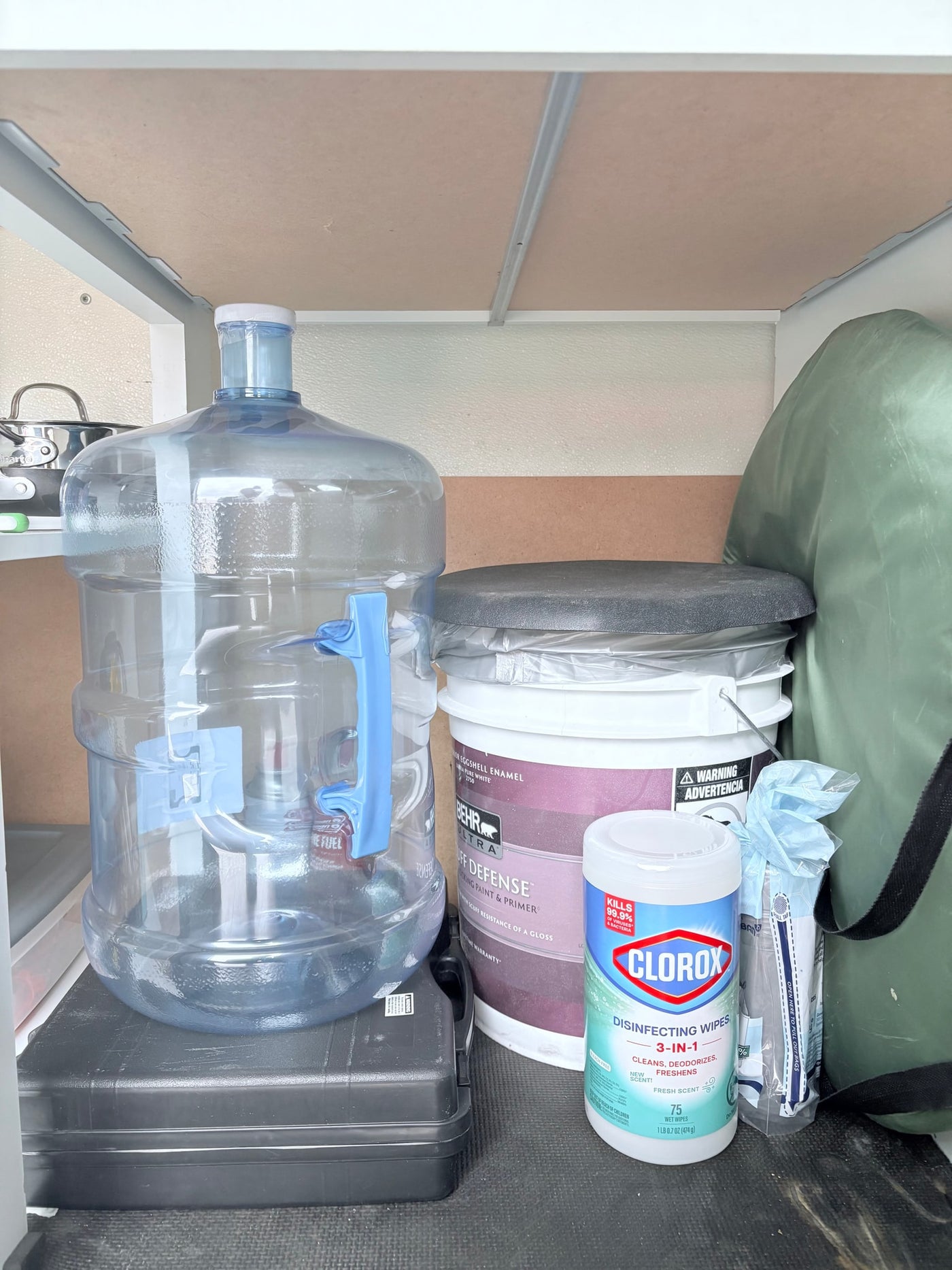 RV rental storage: water jug, paint, Clorox wipes, and travel essentials neatly organized under a shelf. — photo 10