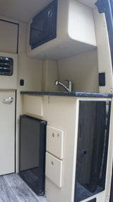 RV rental: Modern kitchenette features microwave, sink, mini-fridge, and sleek storage solutions.