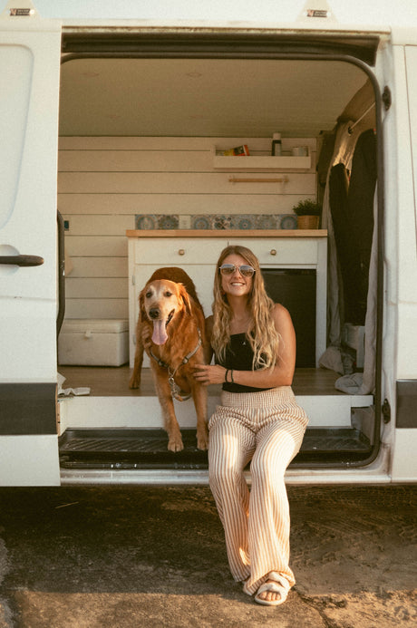A smiling woman and her golden retriever in a cozy rv rental camper van. Perfect for pet-friendly travel.