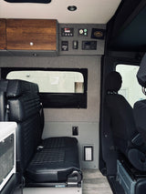 Interior of a modern camper van (RV rental) featuring plush black seating, smart control panels, and custom storage.