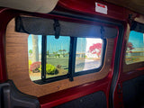 RV rental camper van interior. Wood-paneled windows with roll-up shades reveal a sunny marina view.