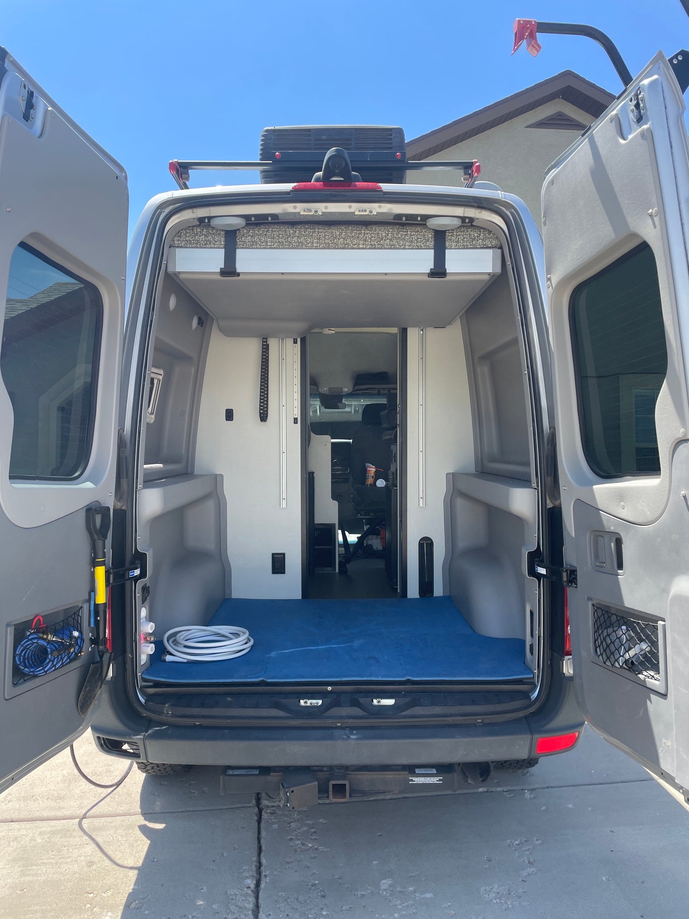 Spacious RV rental camper van with open rear doors, revealing ample storage and a blue floor mat, ready for your next trip. — photo 7