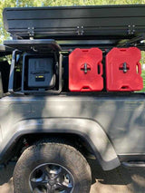 An overlanding rig: grey Jeep with a rooftop tent, red RotopaX, and storage boxes. Ideal for an RV rental for off-road camping.