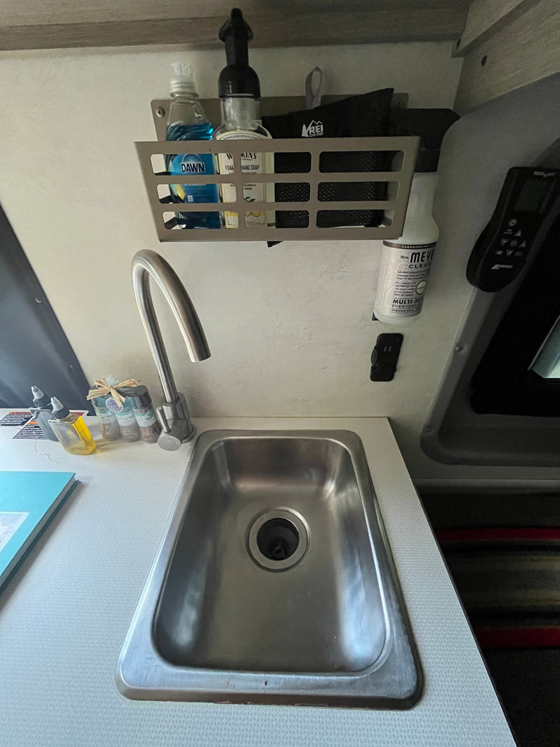 Compact RV rental kitchen features a stainless steel sink, gooseneck faucet, organized soaps, cleaner, and spices. — photo 10