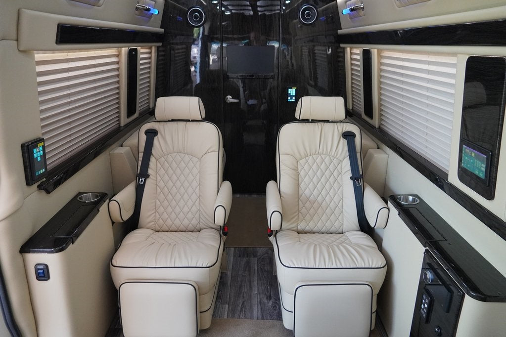 Luxury RV rental interior: two plush cream captain's chairs, panels, TV for premium comfort.