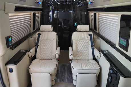 Luxury RV rental interior: two plush cream captain's chairs, panels, TV for premium comfort.