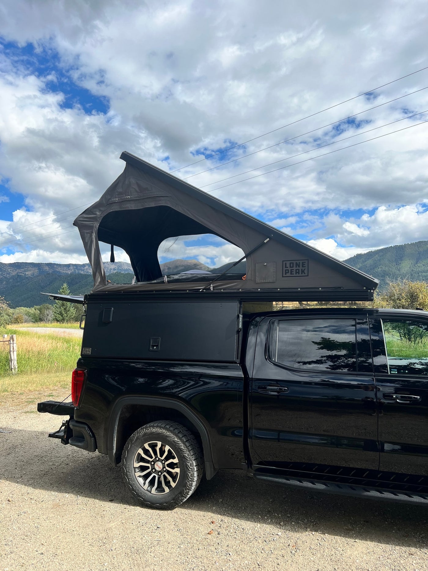 Black pickup truck with an open Lone Peak rooftop tent & bed camper, a unique rv rental for scenic mountain camping. — photo 15