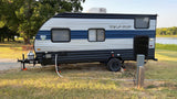 Experience nature with this RV rental. A travel trailer is set up lakeside with utilities, perfect for camping and outdoor travel.