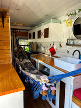 RV rental interior features a full hammock, compact kitchen, and custom wood paneling. Perfect for van life.