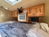 Experience comfort in this RV rental! Features include a cozy bed, wooden cabinets, AC, and charging station for your travels.