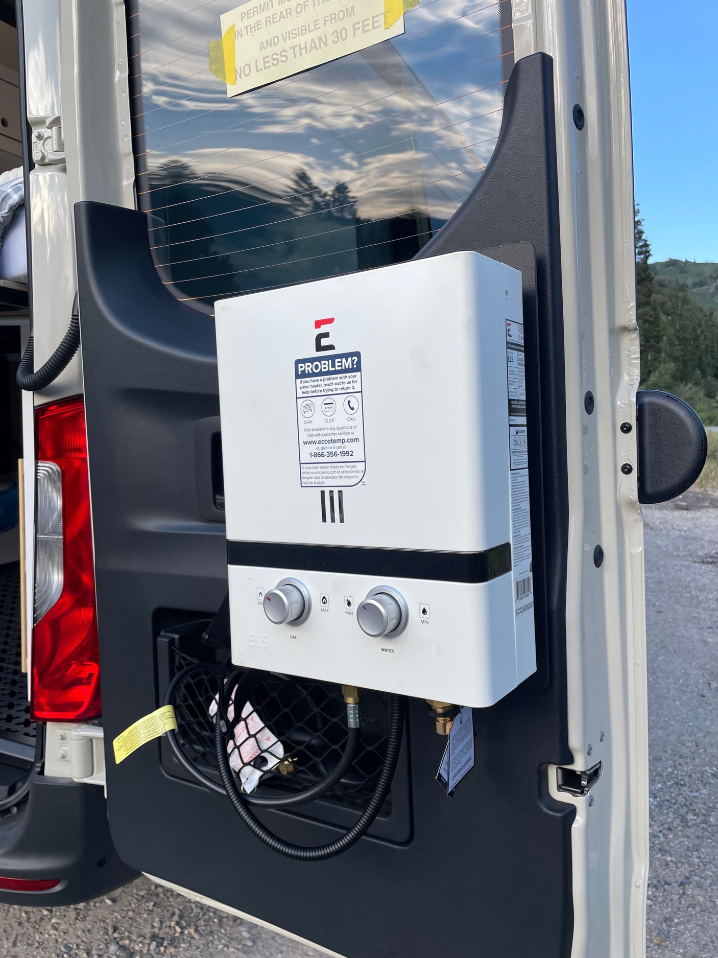 This RV rental van features a mounted Eccotemp portable water heater on the rear door, perfect for outdoor showers.