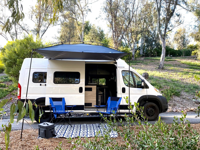 A white camper van, perfect for RV rental adventures, parked with an extended awning, outdoor chairs, and cooler. — photo 20