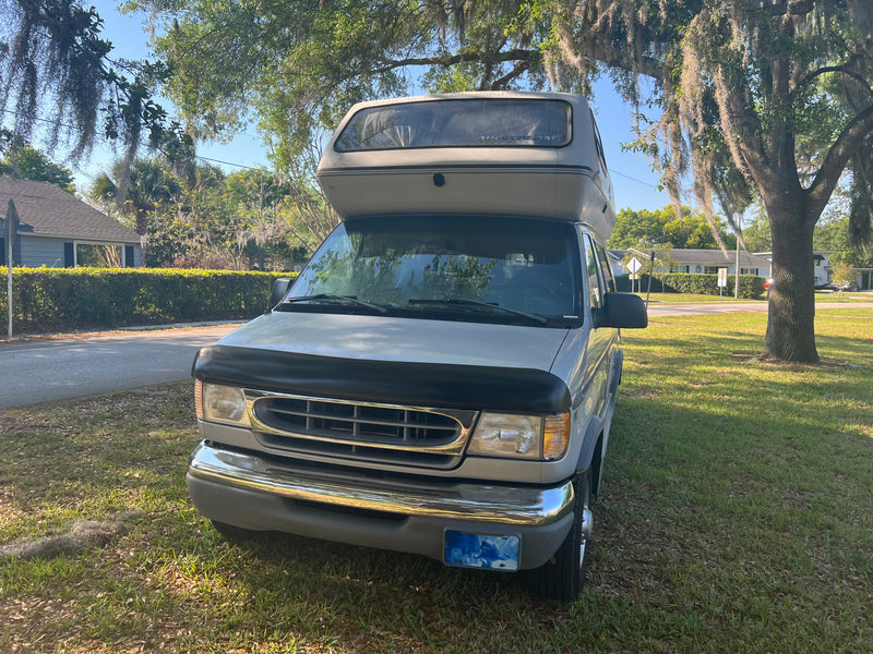 Airstream camper van RV rental parked on grass by road under Spanish moss trees. Front view of gray van. — photo 6