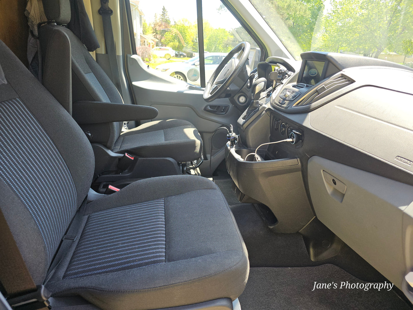 RV rental Ford van interior: front seats, dashboard, and sunny view. Ready for comfortable travel and adventure.
