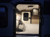 Step into this cozy RV rental: compact interior features a made bed, storage, and visible fire extinguisher for safety.