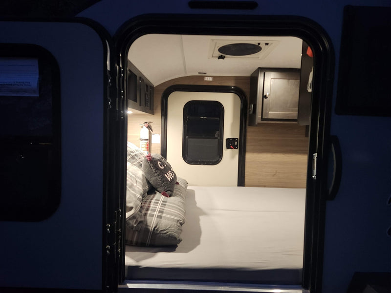 Step into this cozy RV rental: compact interior features a made bed, storage, and visible fire extinguisher for safety. — photo 3