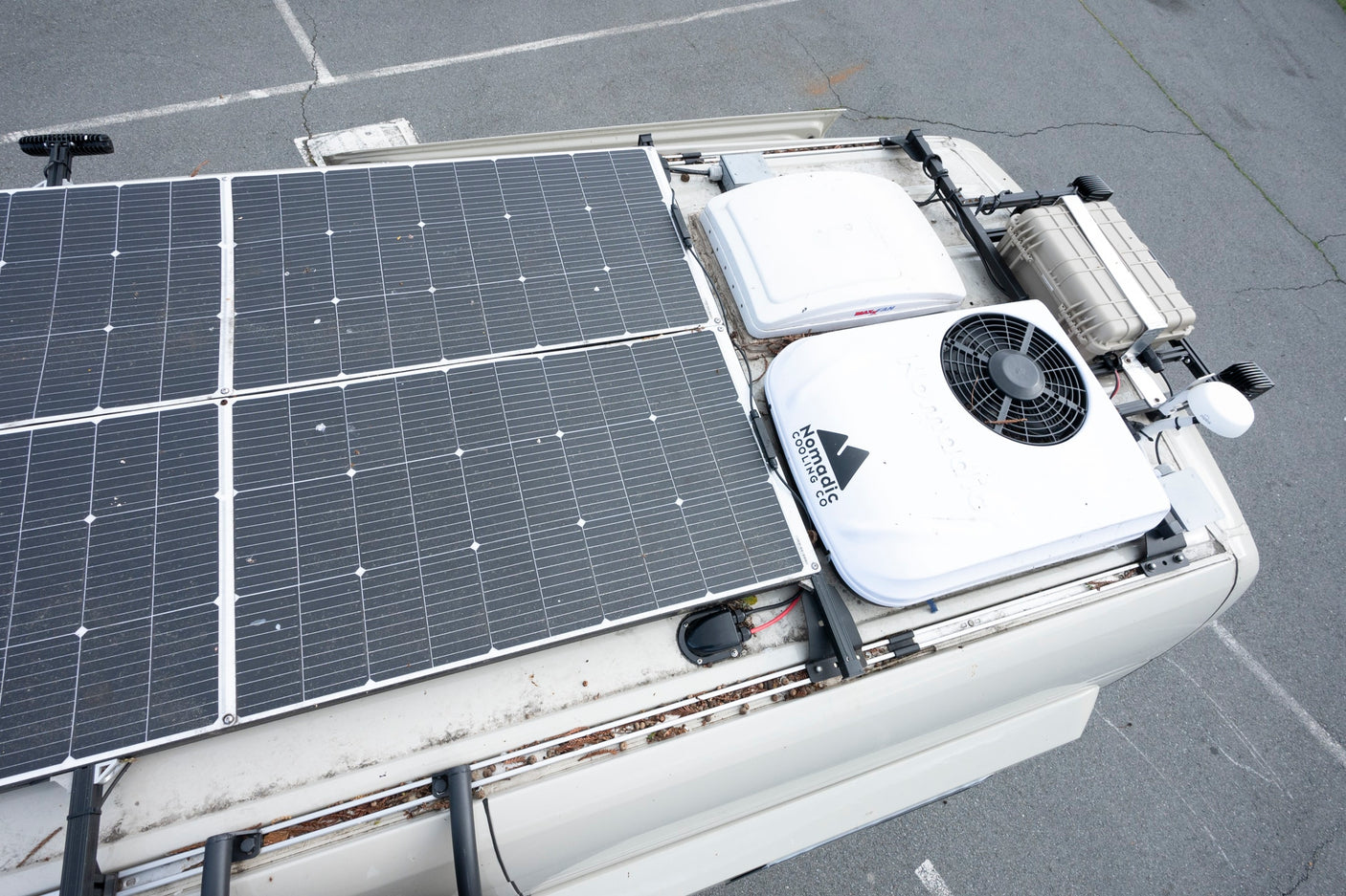 Overhead view of an RV rental's roof with large solar panels, Nomadic Cooling AC, and MaxxAir fan for comfortable off-grid trips.