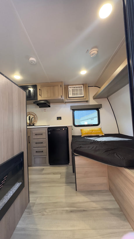 Inside a modern rv rental, featuring a kitchenette, sleeping area, AC, and a fireplace for comfort.