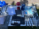 RV rental kitchen prep: collapsible basins, various cooking utensils, knife set, coffee pot, and camp supplies.